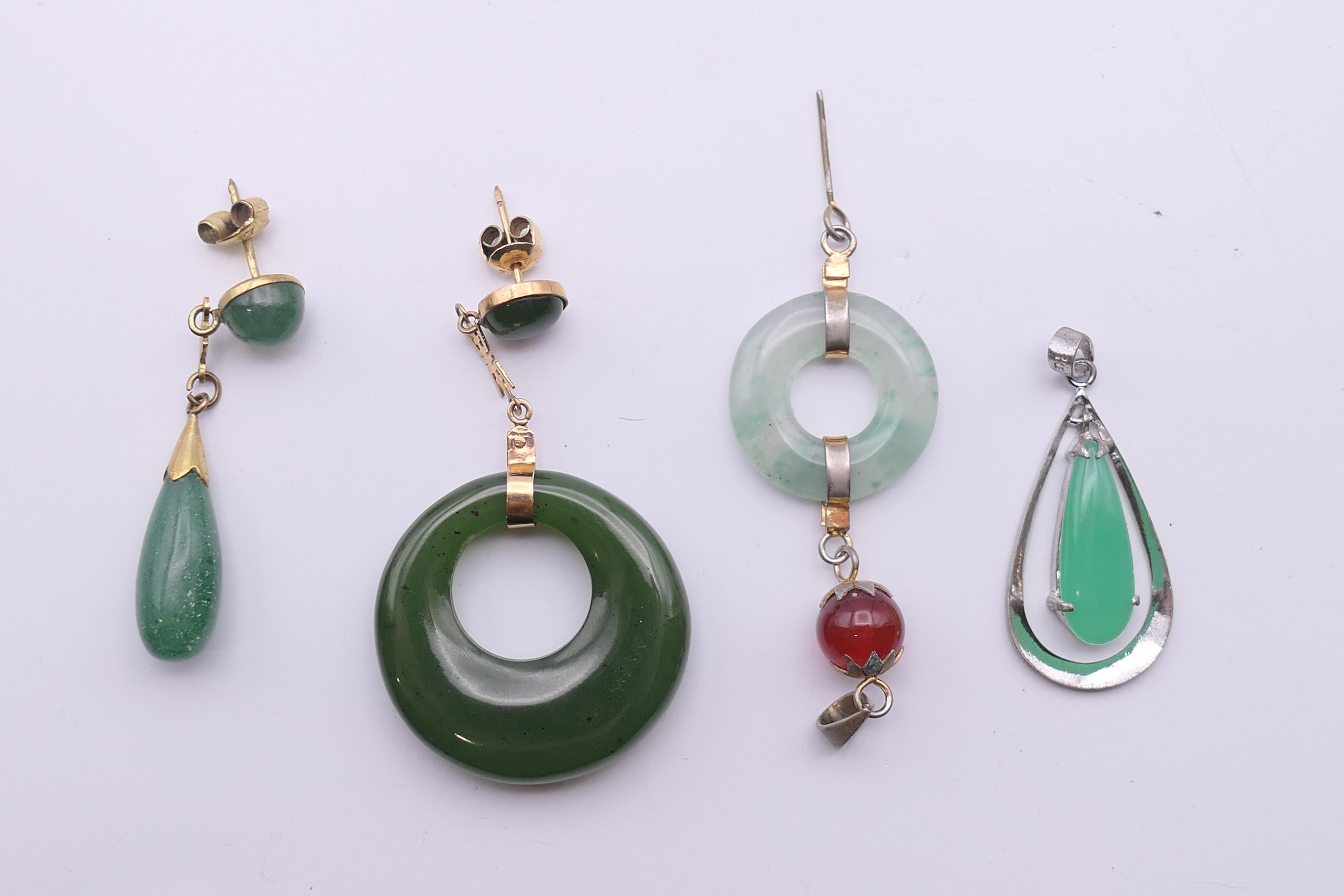 Four jade pendants and earrings. The largest 5 cm high.