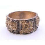 A gilt metal bracelet decorated with various deities. Internal width approximately 5.5 cm.