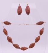 An Oriental carved wooden bead necklace and matching earrings. The necklace 36 cm long.