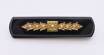 An unmarked gold onyx and seed pearl brooch. 5.5 cm long.