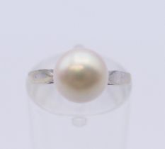 An 18 ct white gold solitaire pearl ring. Ring size I/J. 3.1 grammes total weight.