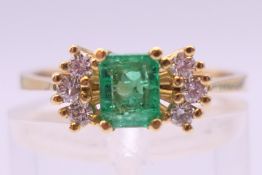 An unmarked 18 ct gold emerald and diamond ring. Ring size M.