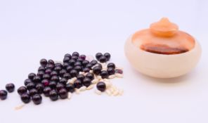 An alabaster pot with mixed beads. 6 cm diameter.