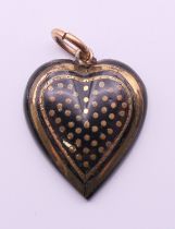 An unmarked gold inlaid tortoiseshell heart form pendant. 2.5 cm high.