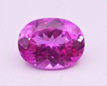 A 25.50 carat oval pink synthetic sapphire. 2 cm long.
