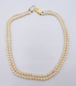 A two strand pearl necklace with 9 ct gold clasp. 33 cm long.