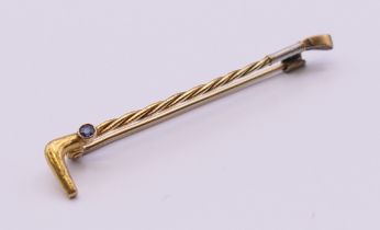A 15 ct gold sapphire set riding crop form brooch. 5 cm long. 2 grammes total weight.