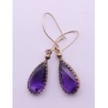 A pair of gold and amethyst drop earrings. 2 cm high.
