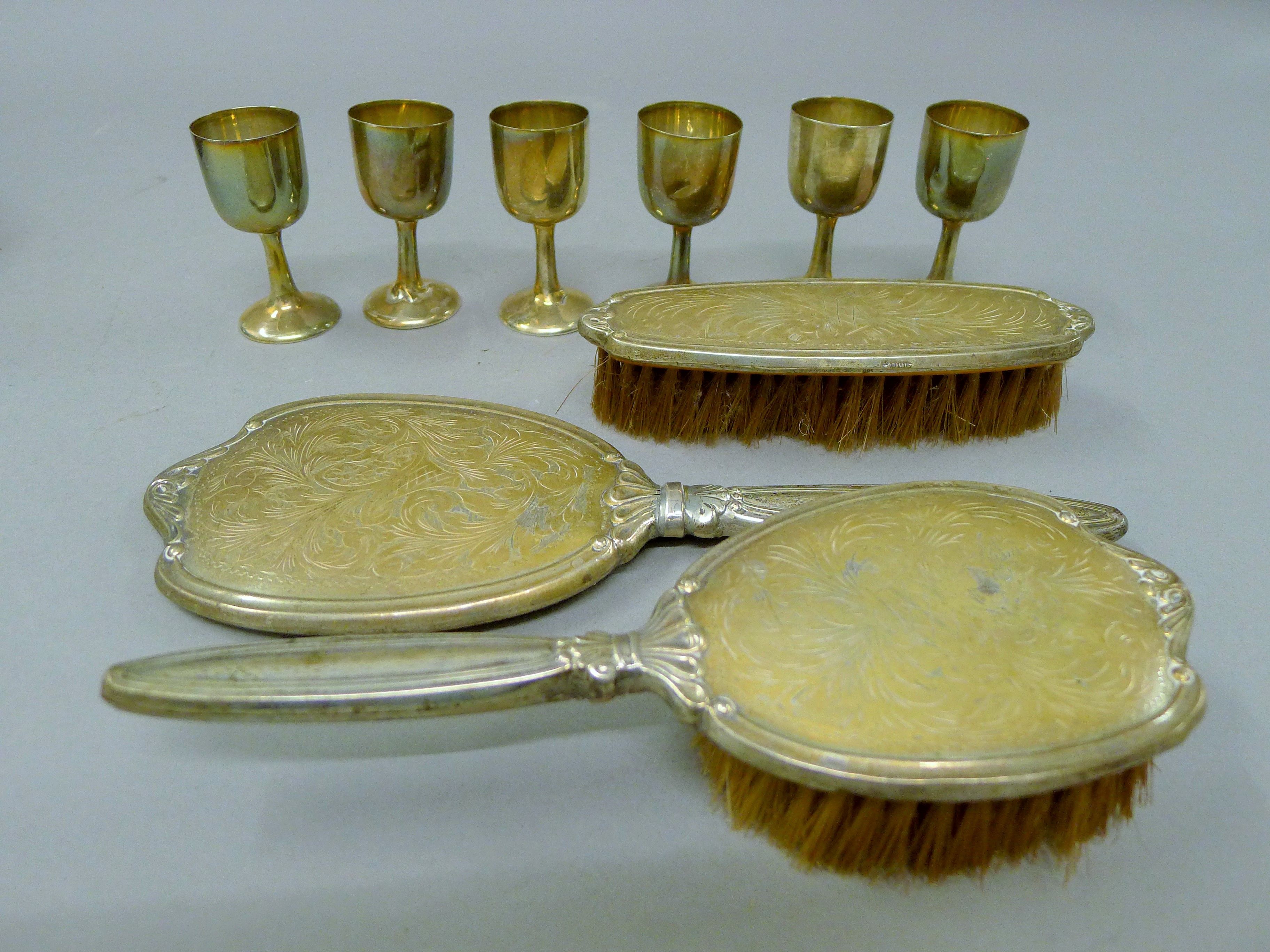Six small silver wine cups, two sterling silver brushes and a mirror. The cups each 7.5 cm high.