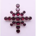 A 19th century unmarked gold and garnet snowflake brooch. 4.5 cm wide.