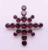 A 19th century unmarked gold and garnet snowflake brooch. 4.5 cm wide.