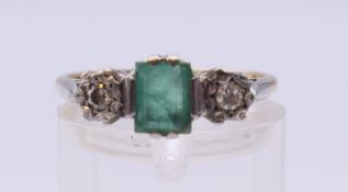 An 18 ct gold and platinum ring set with an emerald and two diamonds. Ring size N.