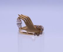 An 18 ct gold diamond ring in the form of a hand. Ring size N. 2.8 grammes total weight.