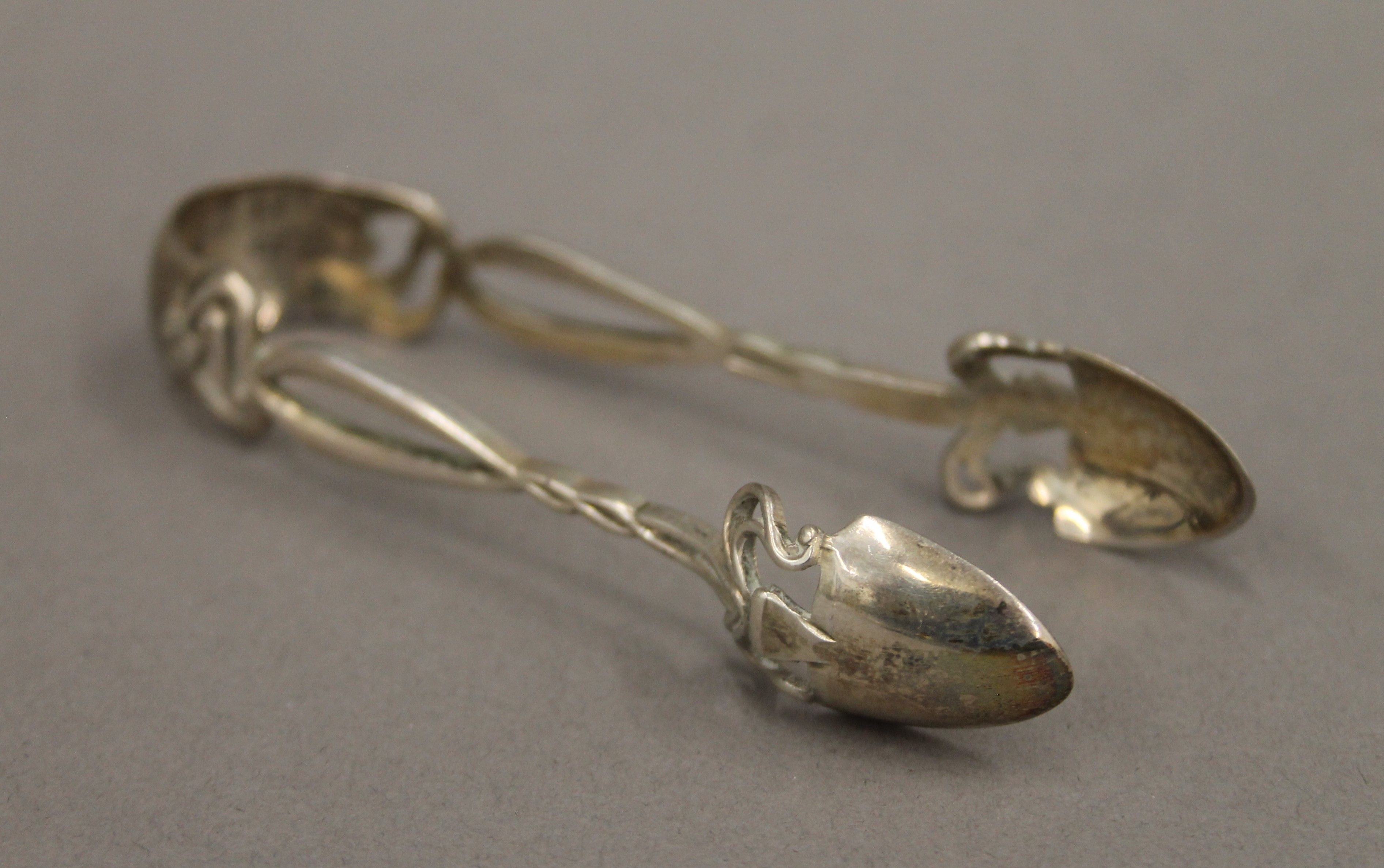 A cased set of Art Nouveau silver teaspoons and tongs. The case 54 cm wide. 112.4 grammes. - Image 3 of 16