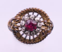 An unmarked 18 ct gold ruby and diamond cluster ring. Ring size O. 6.1 grammes total weight.