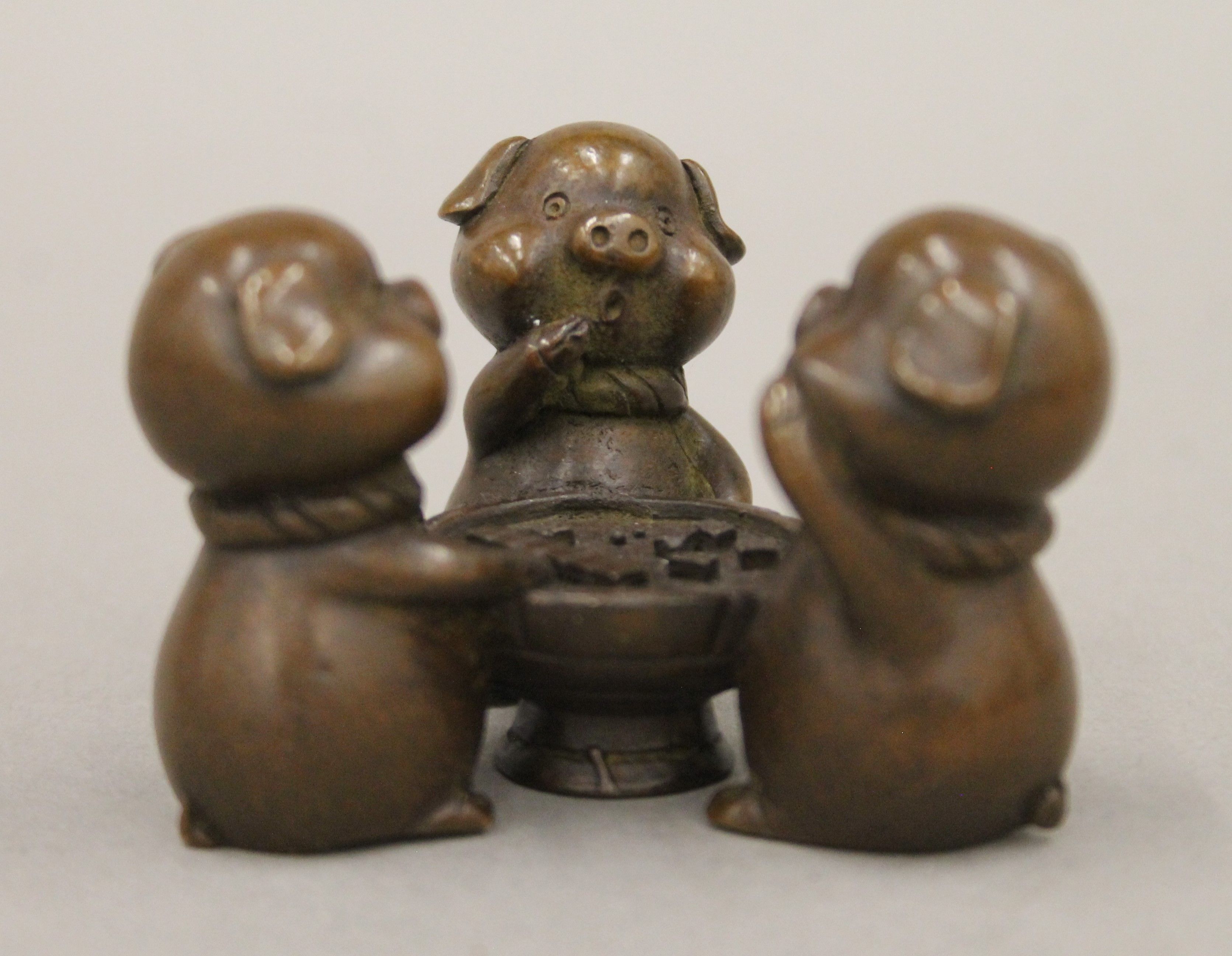 A bronze model of three pigs playing a game. 4.5 cm high.