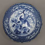 An Oriental blue and white porcelain dish decorated with peacock on prunus tree. 25 cm diameter.