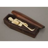 A wooden model of a coffin enclosing a carved bone skeleton. 12 cm long.