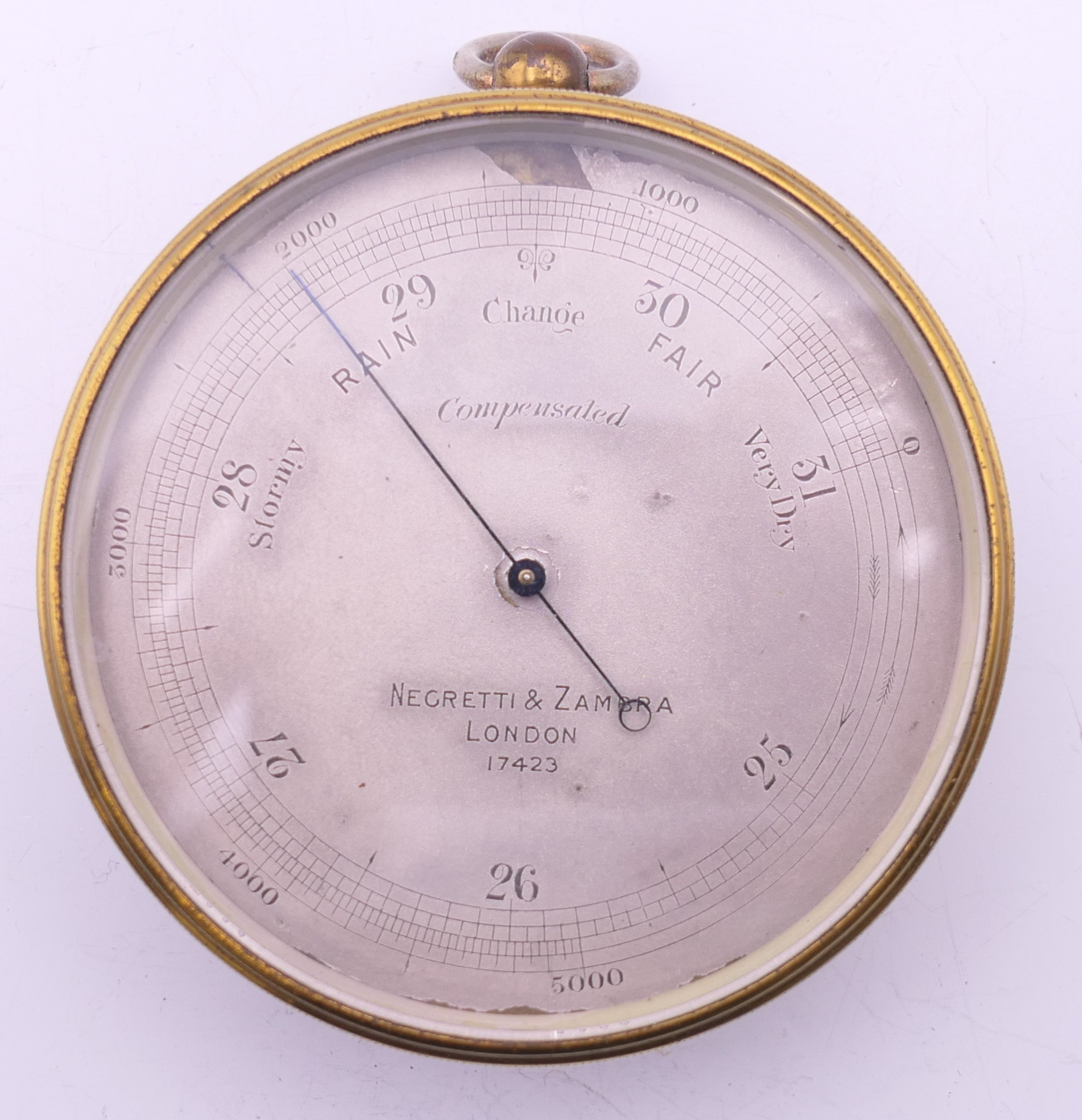 A Negretti & Zambra of London brass barometer, in original case, numbered 17423. 7 cm diameter.