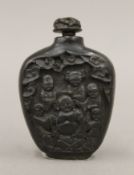 A Chinese black snuff bottle depicting a seated Buddha and attendants. 7 cm high.