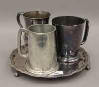 A silver plated salver and three tankards. The former 25 cm diameter.