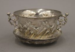 A silver twin handled cup and saucer. The cup 13 cm wide. 189.2 grammes.