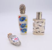 Three glass scent bottles, one with silver cladding. The largest 7 cm high.