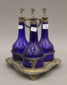 A silver plated three bottle decanter stand with three glass bottles. 27.5 cm high.
