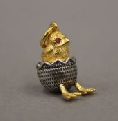 A silver and silver gilt pendant formed as a hatching chick, bearing Russian marks. 2 cm high.