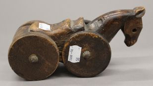 A carved wooden pull along toy horse. 20 cm long.