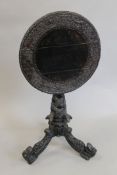 An 19th century Eastern carved tilt top tripod table. 54 cm diameter.
