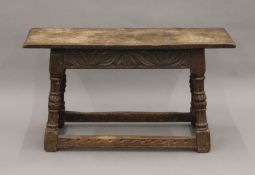 An 18th century carved oak stool. 85.5 cm long.