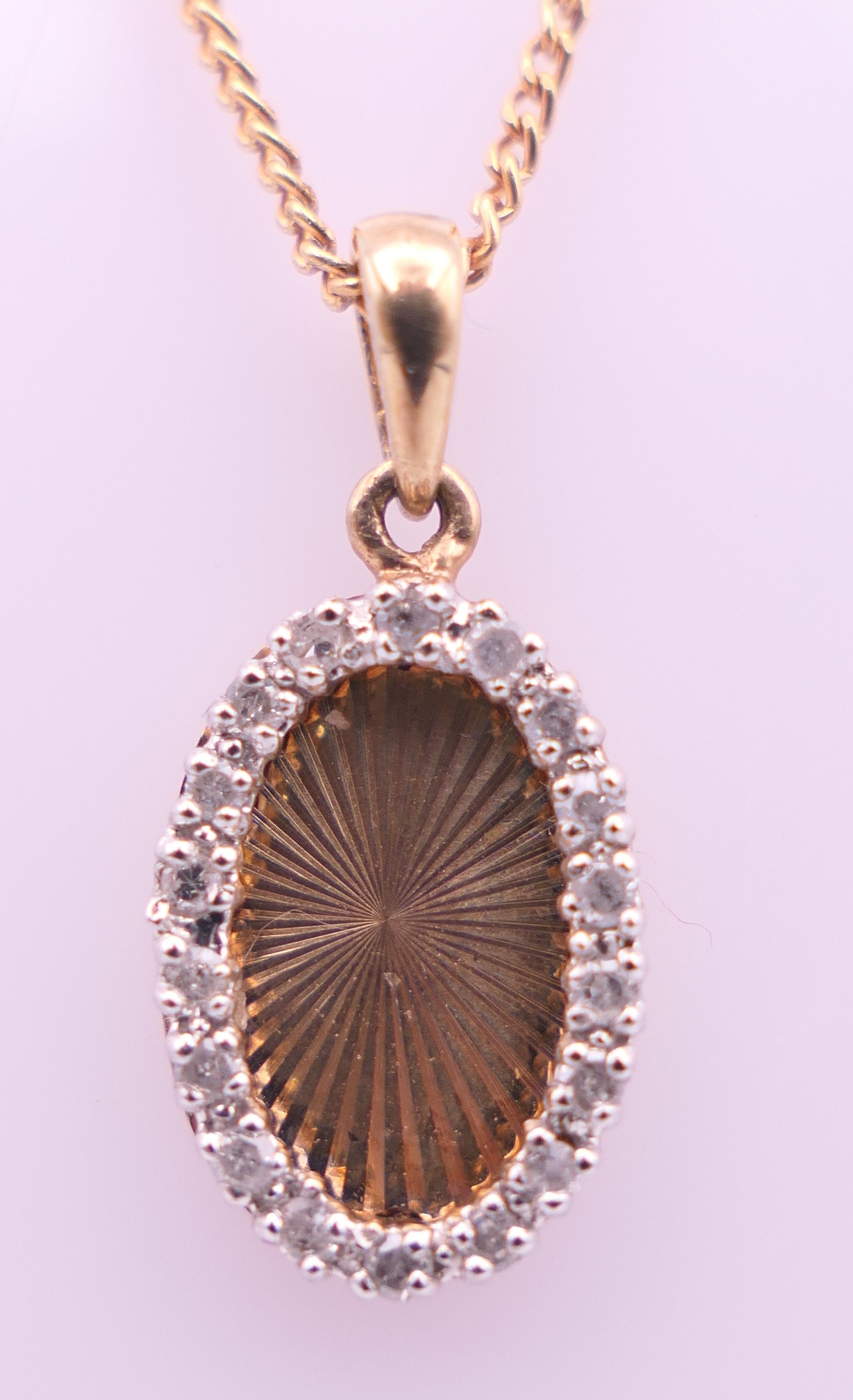 A 9 ct gold and diamond oval pendant on a 9 ct gold chain. Pendant 1.