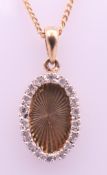 A 9 ct gold and diamond oval pendant on a 9 ct gold chain. Pendant 1.