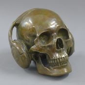 A bronze model of a skull wearing headphones. 14 cm high.