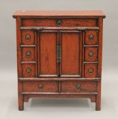 A Chinese red lacquered side cabinet. 73 cm wide.