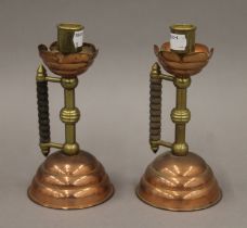 A pair of Christopher Dresser design copper and brass chambersticks. 18.5 cm high.