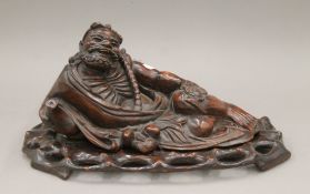 A Chinese carving of an Immortal, possibly Li Tieguai, mounted on a carved wooden plinth base.