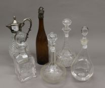 A claret jug, four decanters and a white metal topped bottle. The latter 36.5 cm high.