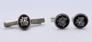 A pair of Chinese silver cufflinks and a tie clip. The latter 5 cm wide.