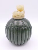 A Chinese round dark green jade snuff bottle with white jade carved bear screw stopper,