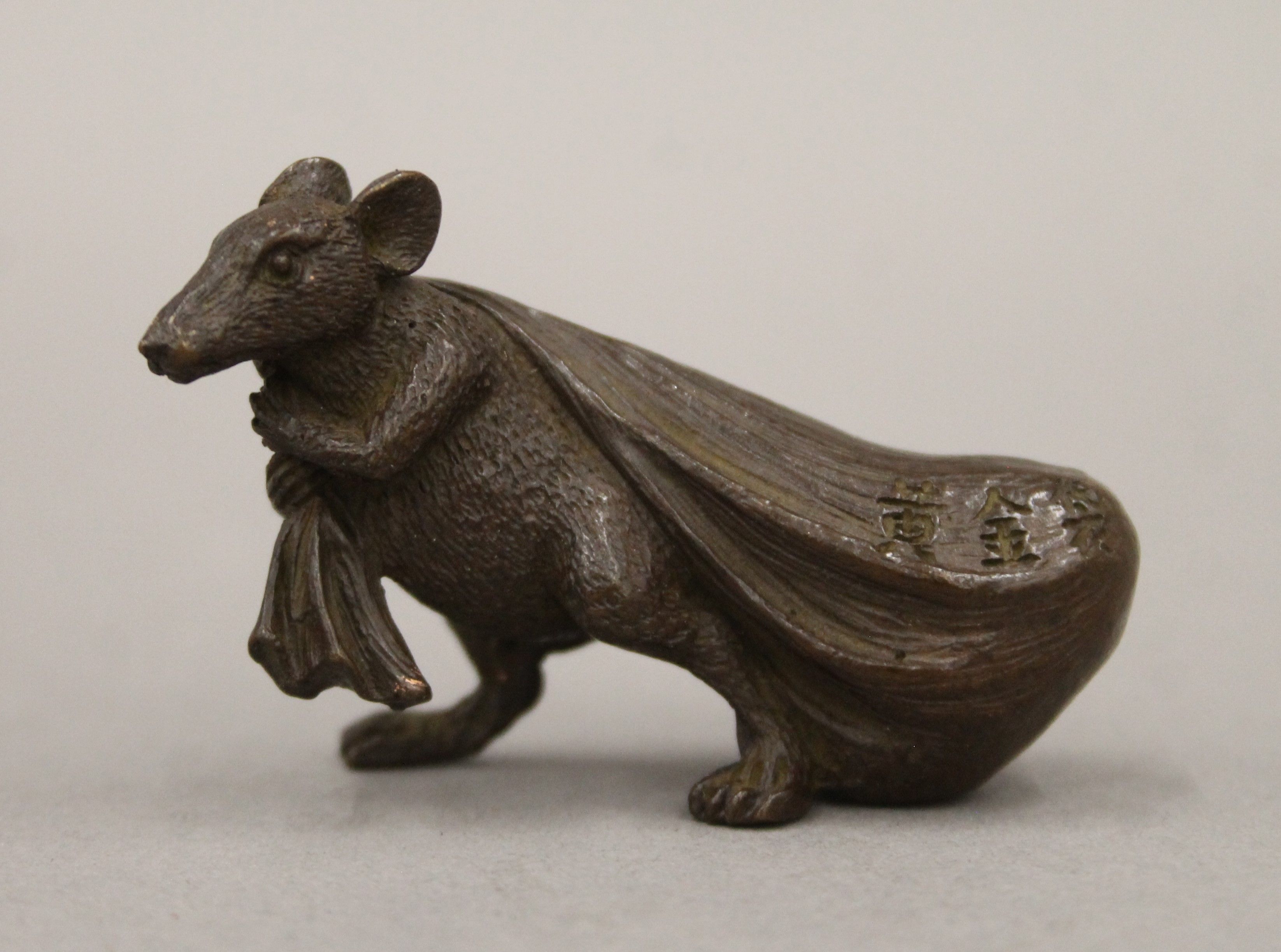 A bronze model of a rat carrying a bag. 3.5 cm high.