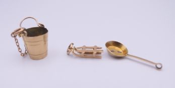 Three 9 ct gold charms. The bucket 1.3 cm high. 3.1 grammes.