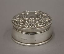 A silver box with repousse decoration to the lid, hallmarked Birmingham 1982. 8.5 cm diameter.