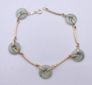 A 14 ct gold and jade disc bracelet. 19.5 cm long. 4.8 grammes total weight.