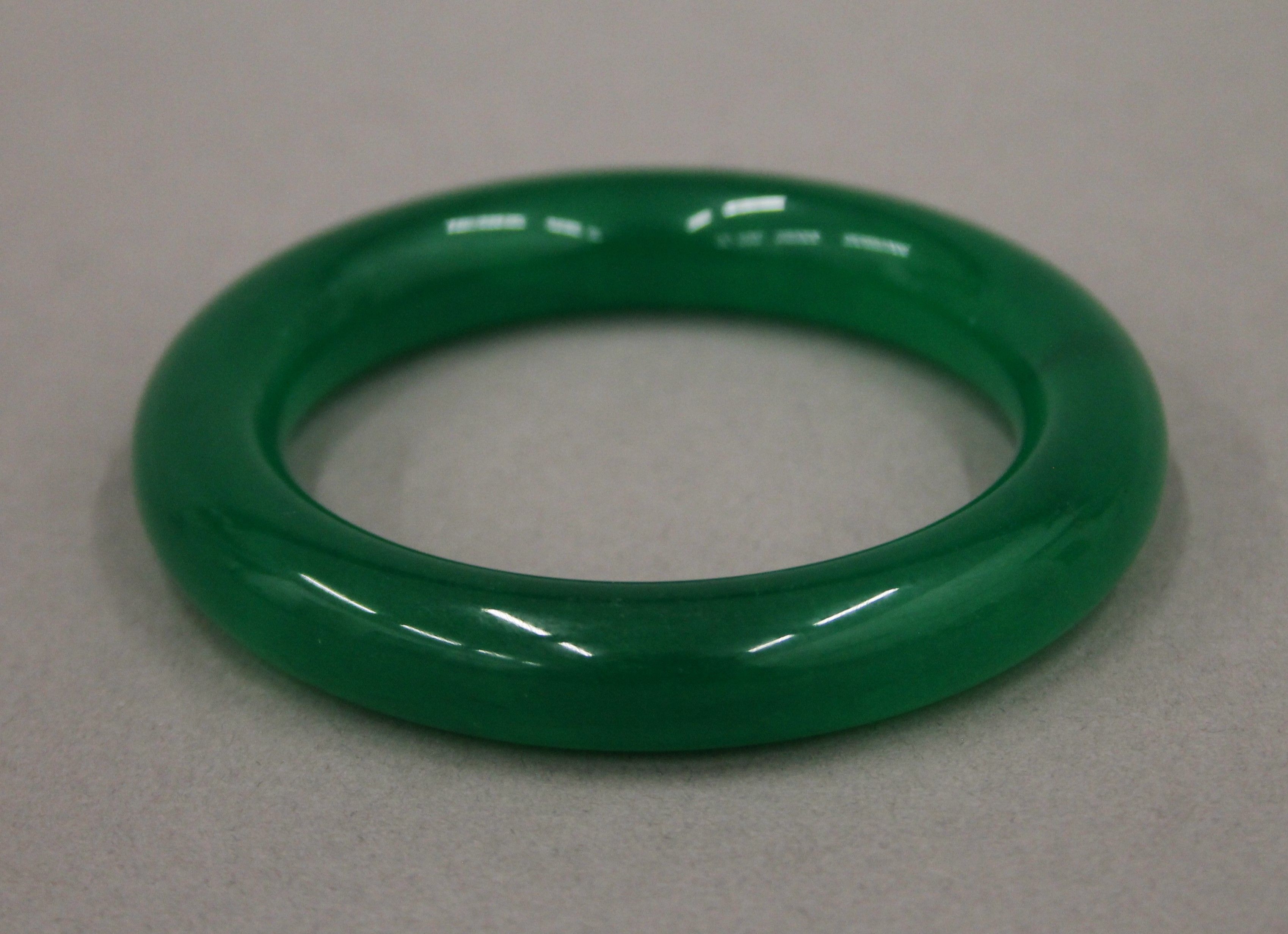 An apple green jade bangle. Approximately 6 cm interior diameter.