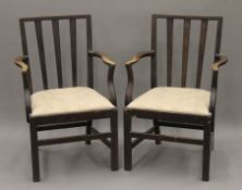 A pair of late 19th/early 20th century oak splat back open arm chairs. 57 cm wide.