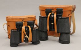 Two cased pairs of binoculars. The largest 19 cm high.