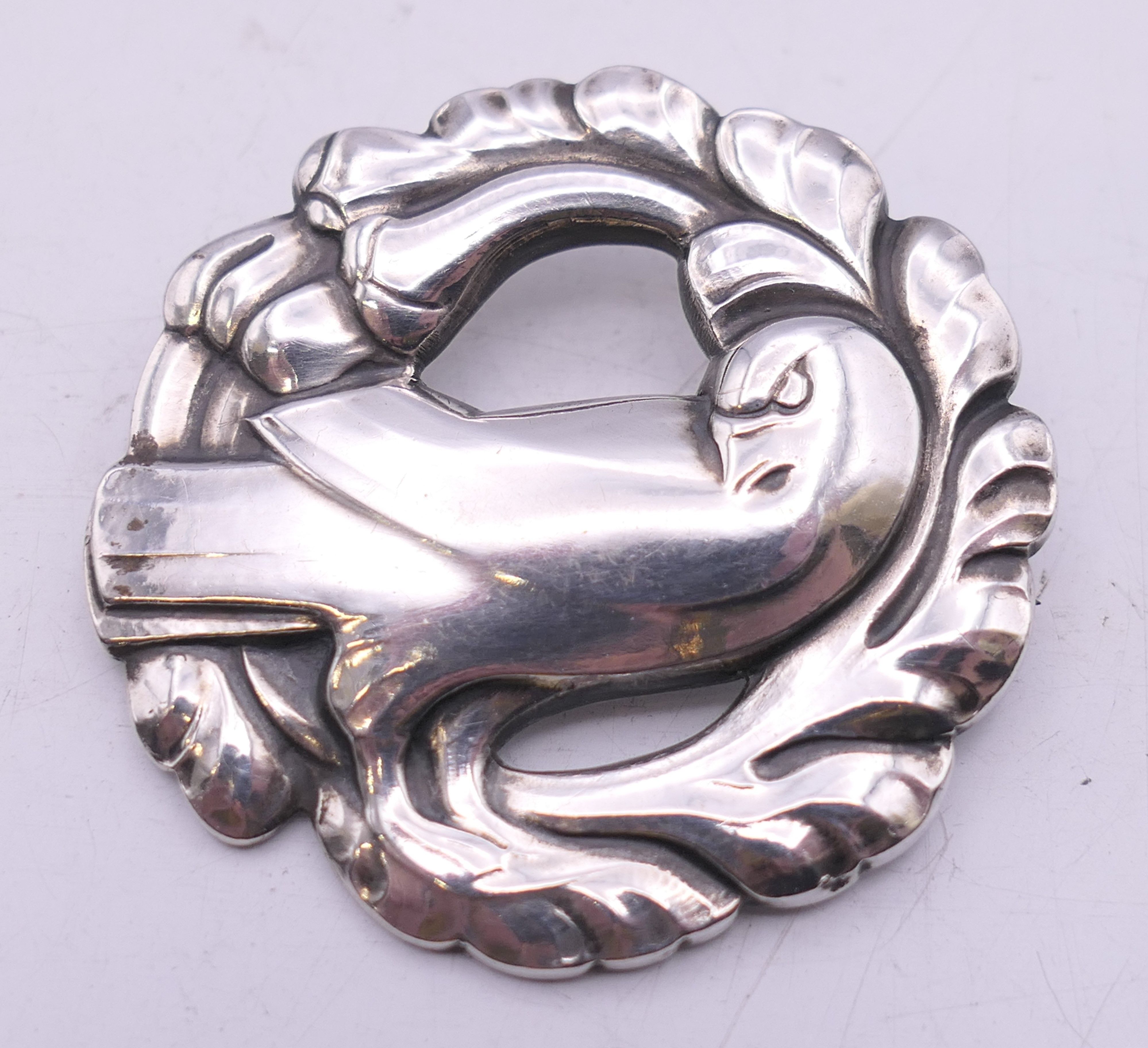A vintage Georg Jensen circular silver brooch with dove design, numbered 165. 4 cm wide.