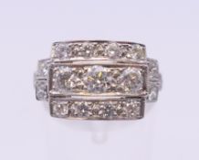 An Art Deco style platinum three row diamond ring. Ring size O/P. 5.2 grammes total weight.